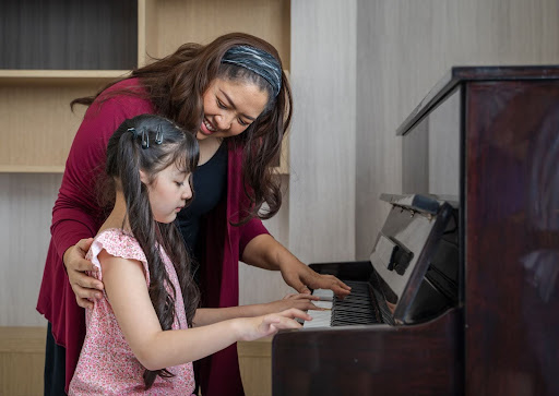 Piano student with her teacher, practicing