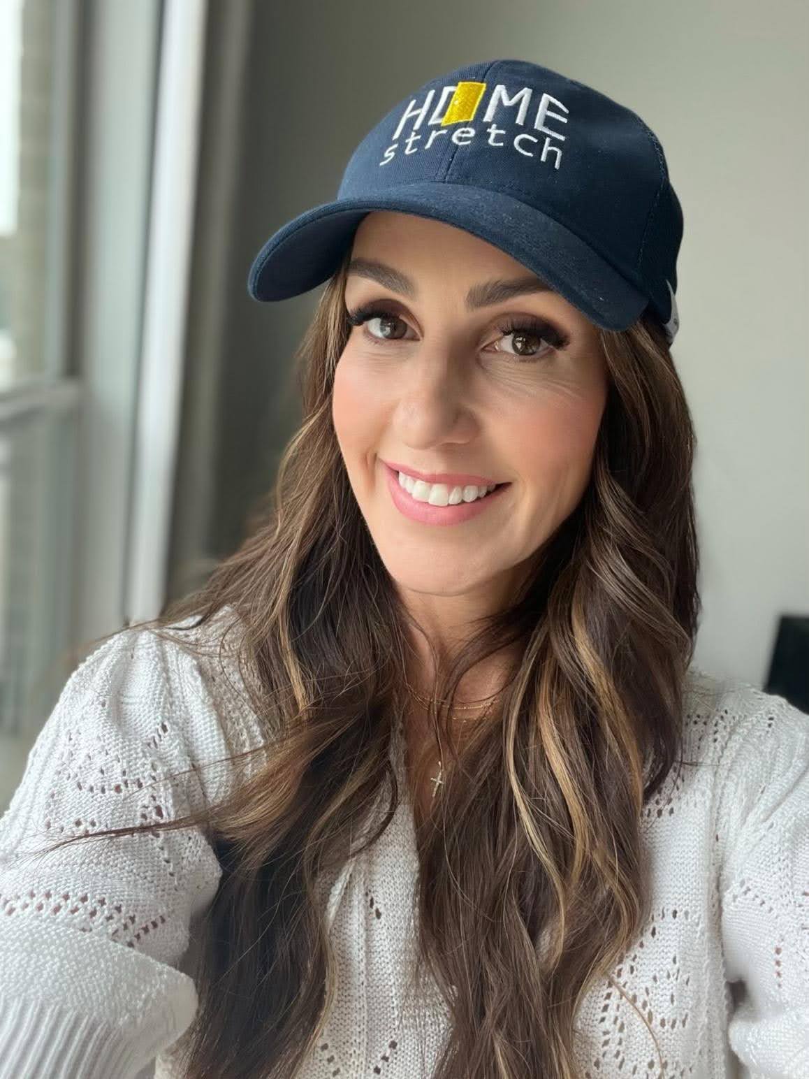 Women taking a selfie with a hat that says "Home Stretch" on it. 