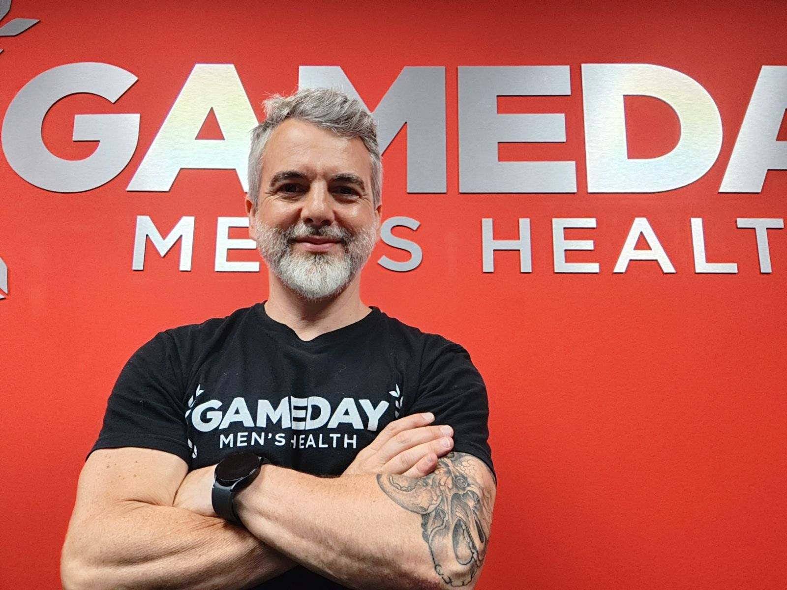 Smiling man standing in front of Gameday Men's Health sign