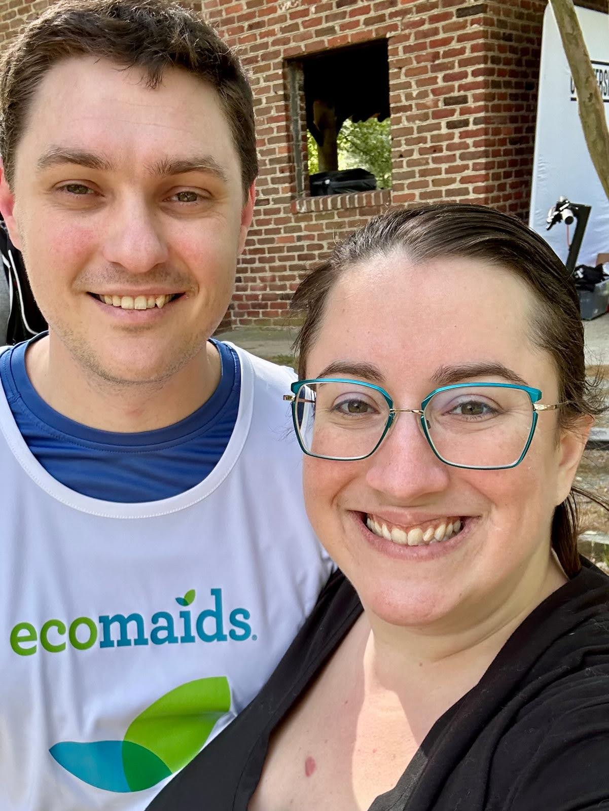 Husband and wife taking selfie, husband is wearing 'ecomaids' shirt. 