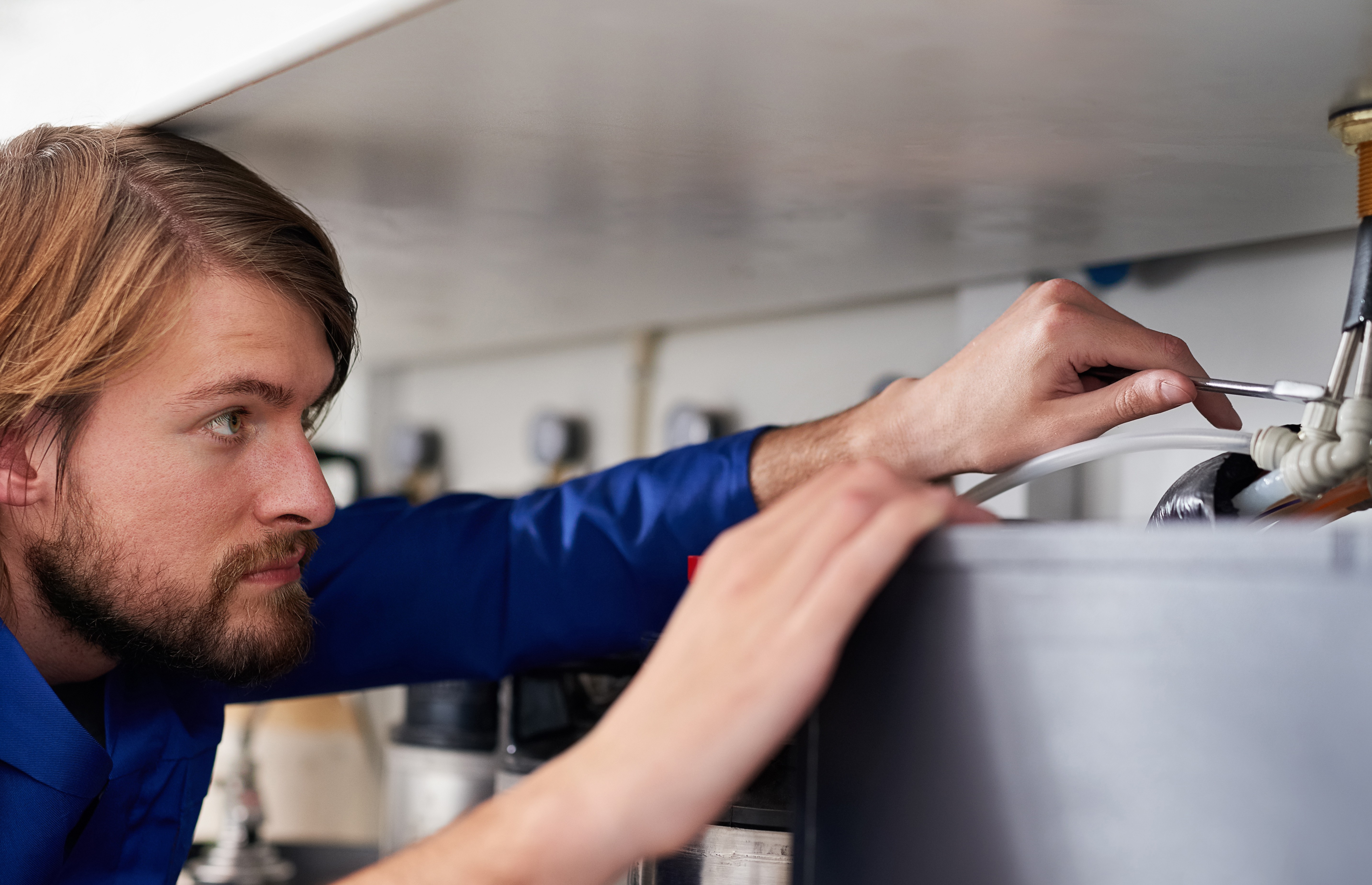 Man in a blue shirt fixing a gasket. 