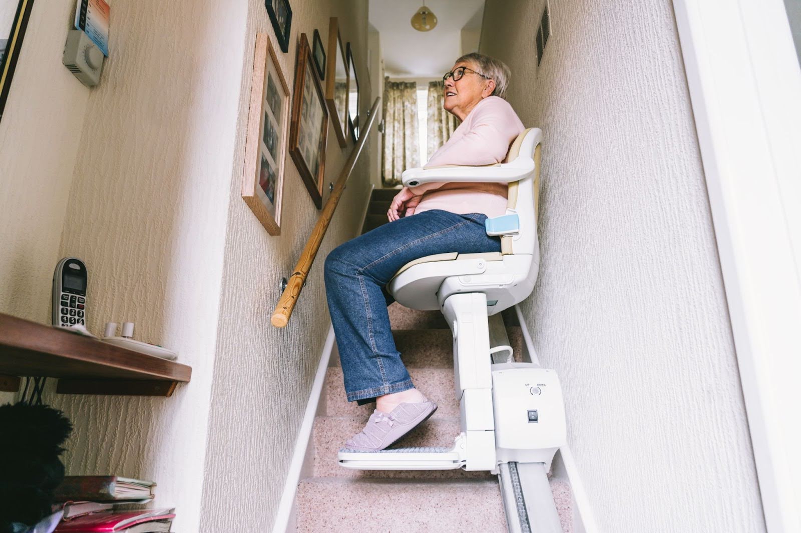 Elderly women at home using a stairlift to get up her stairs.